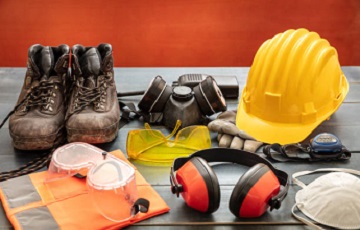 Work safety protection equipment. Industrial protective gear on wooden table, red color background. Construction site health and safety concept